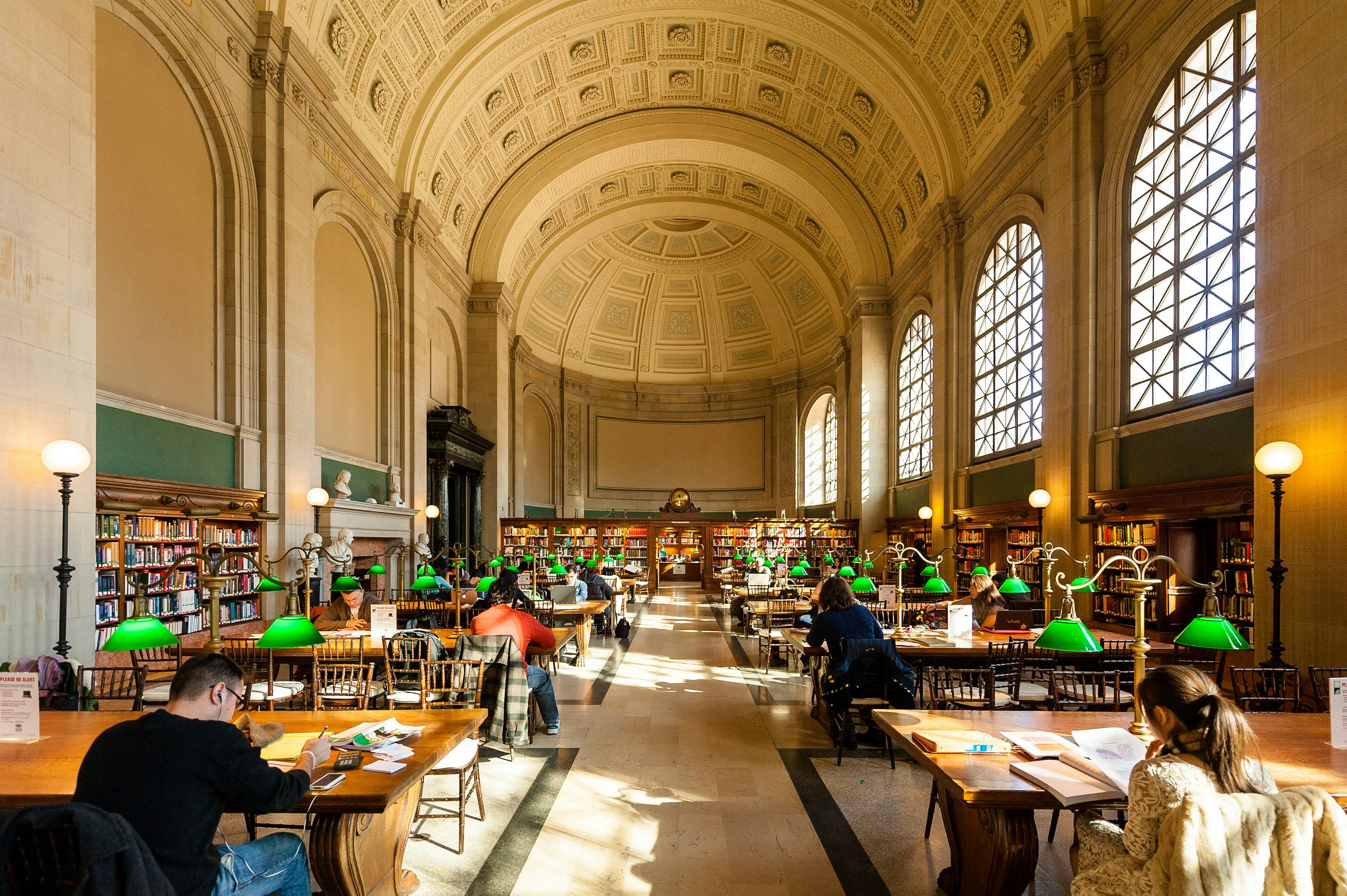 People studing and reading in a large library room with a domed ceiling