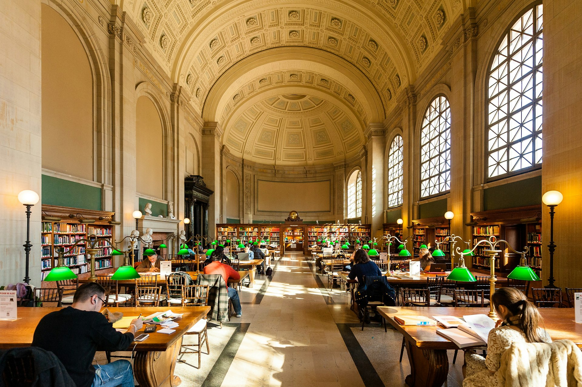 People studing and reading in a large library room with a domed ceiling