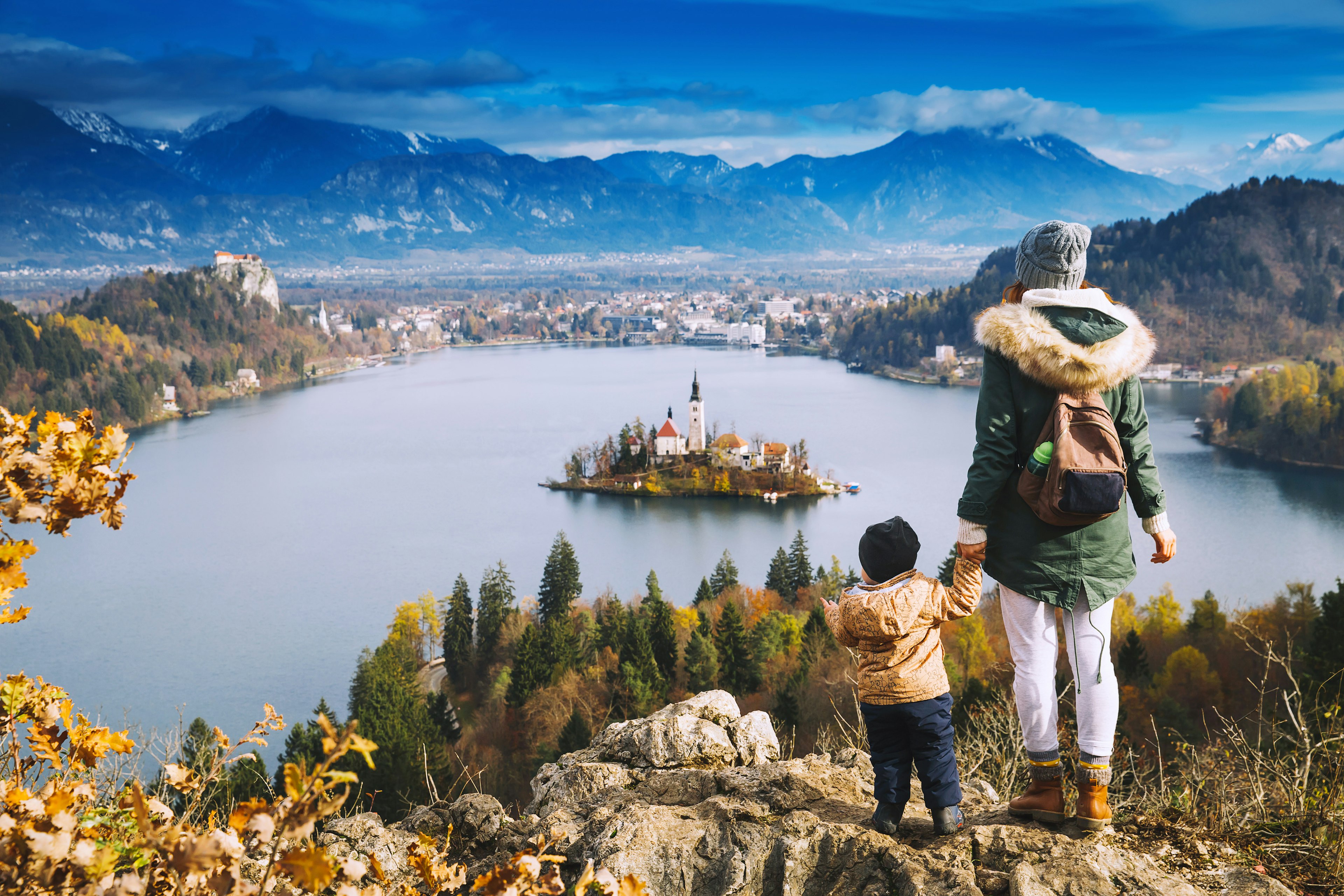 A mother holding her child's hand overlooking Bled Island on Bled Lake.