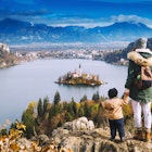 A mother holding her child's hand overlooking Bled Island on Bled Lake.