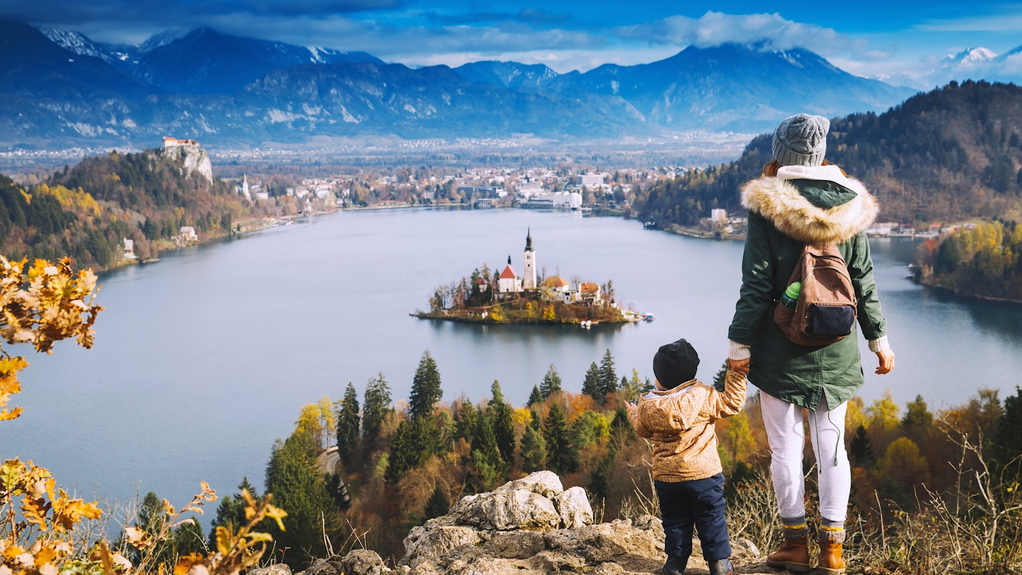 A mother holding her child's hand overlooking Bled Island on Bled Lake.