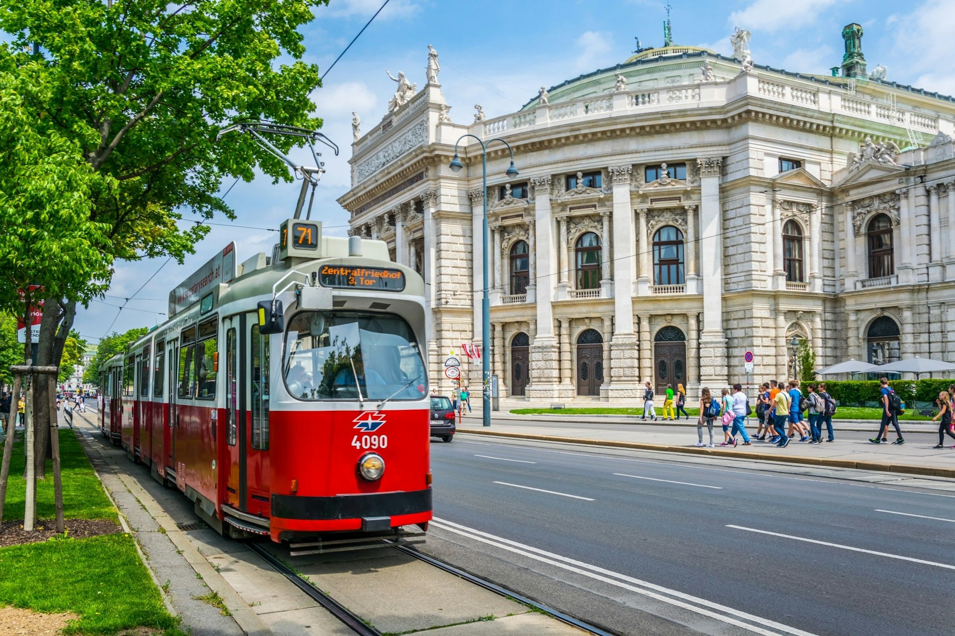 Visitors walk along Vienna's Ringstrasse, past the historic Burgtheater 