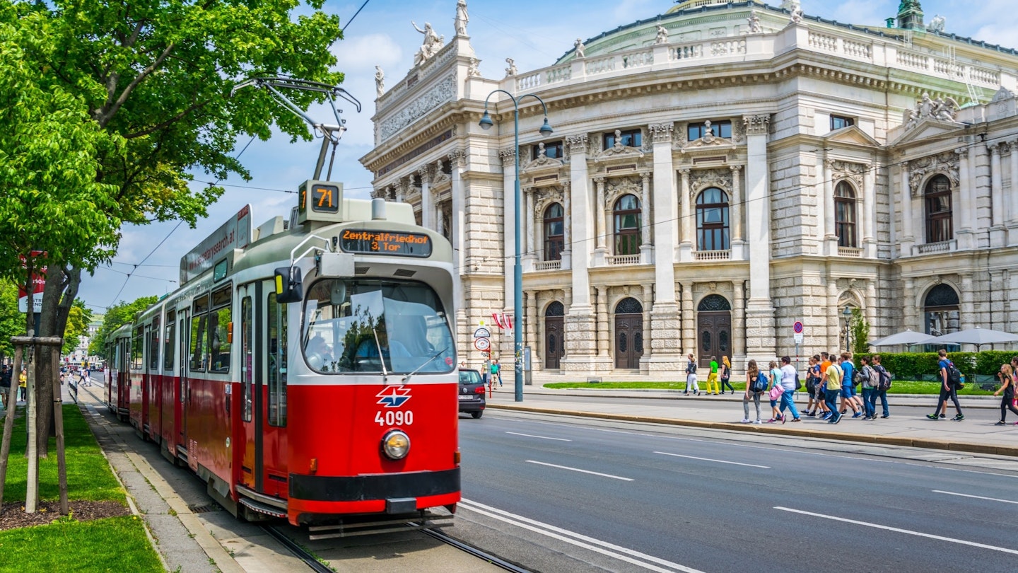 Wiener Ringstrasse with the historic Burgtheater (Imperial Court Theatre) and a traditional red electric tram.