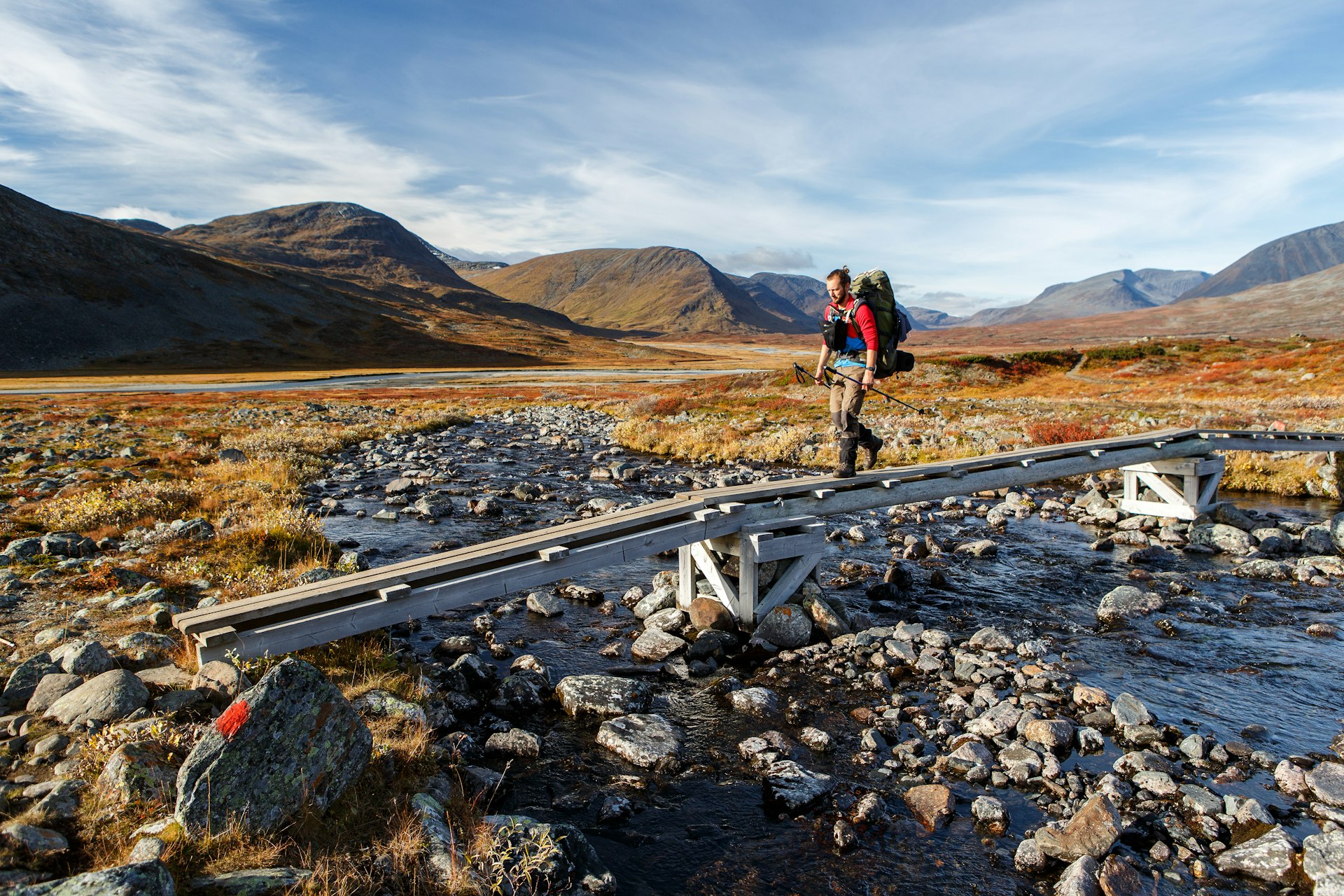 A long-distance hiker on an elevated portion of the Kungsleden hiking trail, over rocky ground in Lapland 