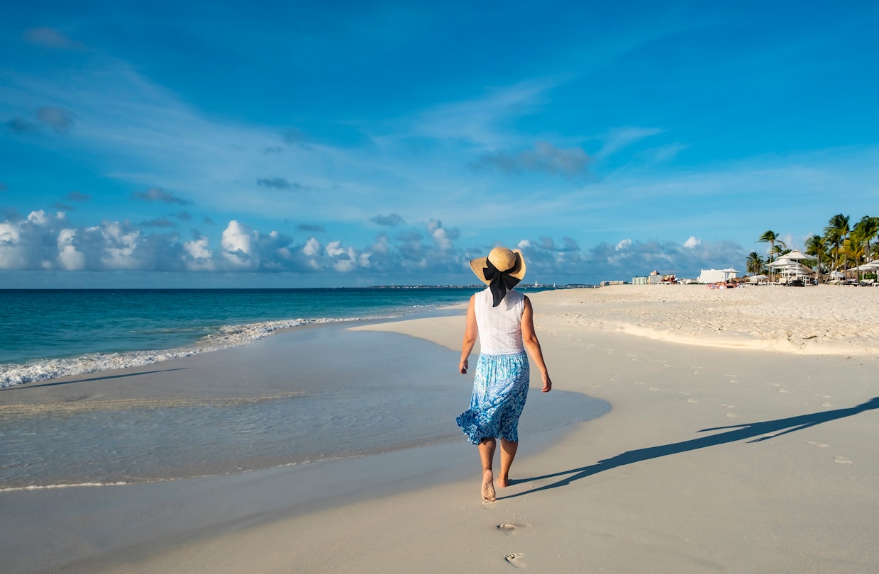 A woman walking barefoot on an Aruba beach