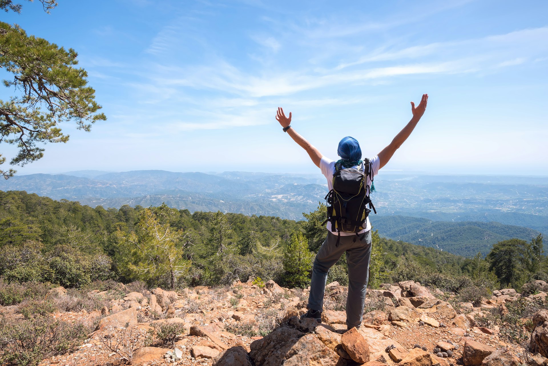Hiker raising arms over views of mountains in Troodos National Forest Park