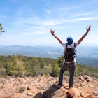 Hiker raising arms over views of mountains in Troodos National Park