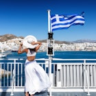 Elegant woman with white dress and hat on a ferry boat in the Cyclades of Greece
