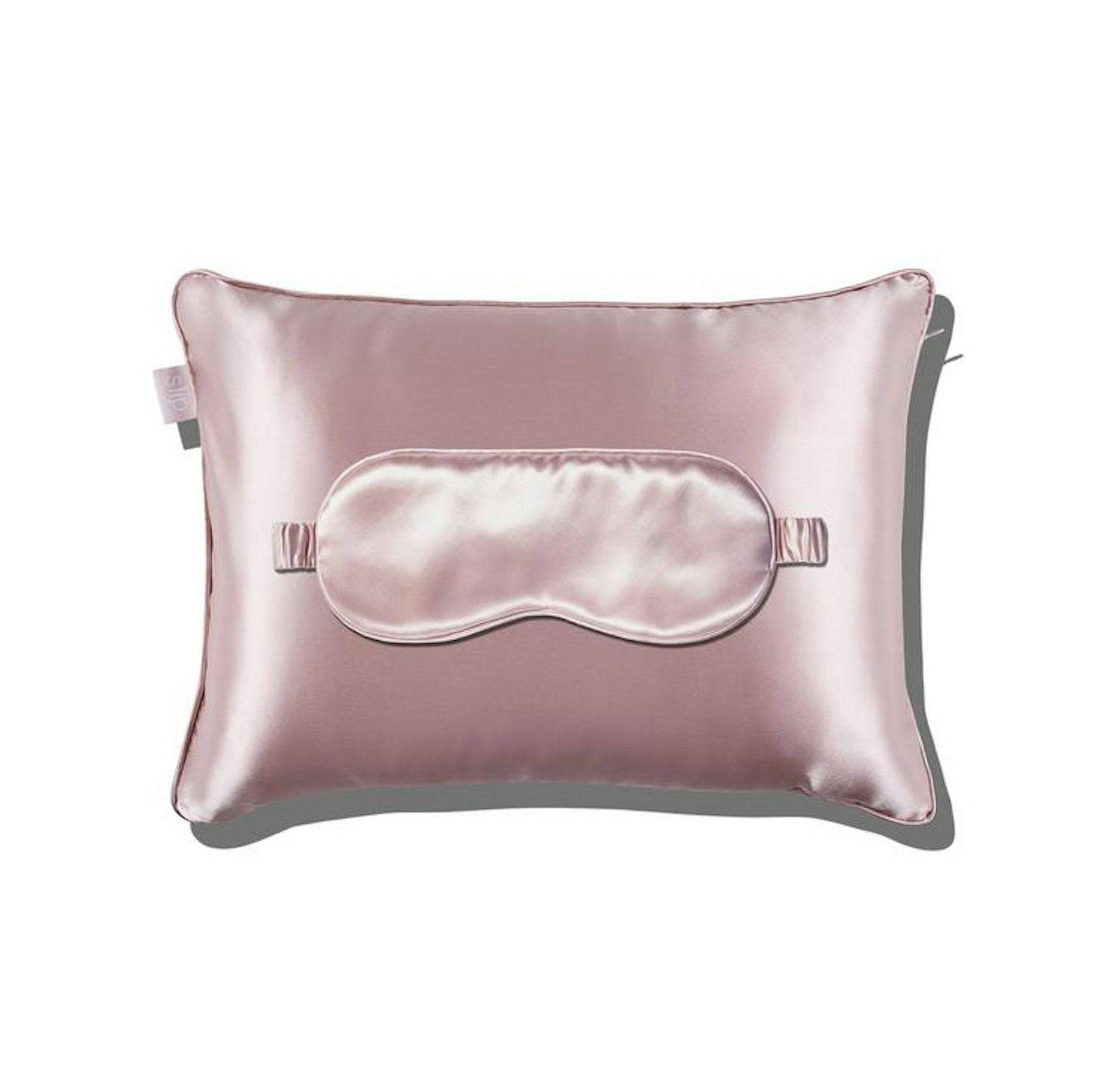 Slip's pink-silk travel set, an eye mask on top of a pillow