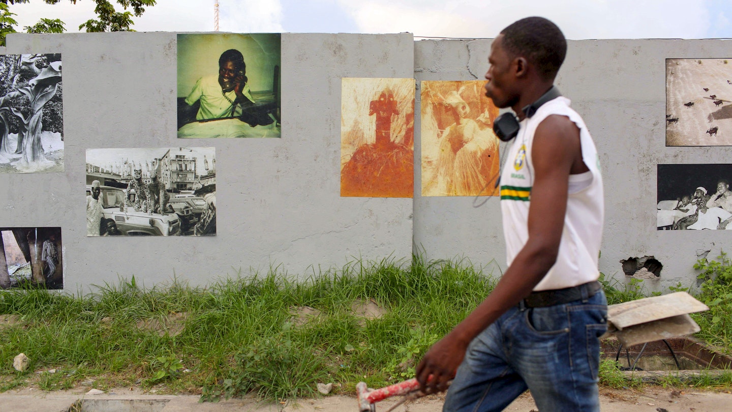 A pedestrian walked by photographs pasted on a wall for the Lagos Photo Festival, years before the Covid-19 pandemic halted all art events and closed museums.