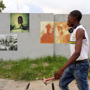 A pedestrian walked by photographs pasted on a wall for the Lagos Photo Festival, years before the Covid-19 pandemic halted all art events and closed museums.