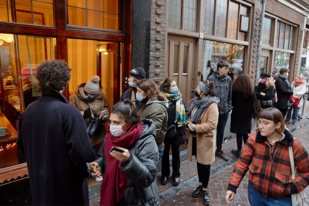 People line up outside a shop selling cookies on December 19, 2021 in Amsterdam ahead of the new Christmas lockdown
