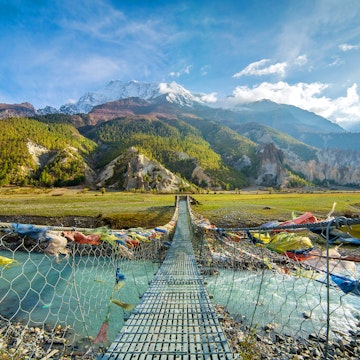 Suspension bridge with buddhist prayer flags on the Annapurna circuit trek in Nepal.