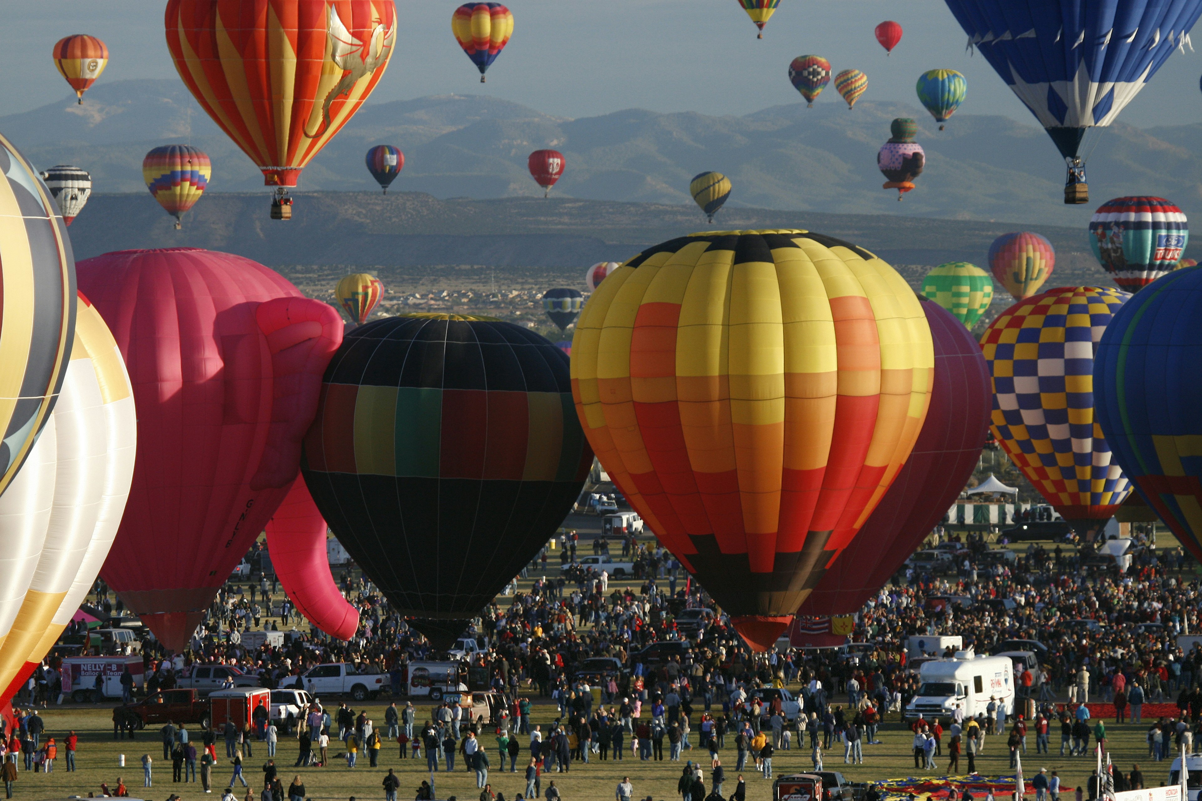 "Albuquerque, USA - October 12, 2007: Mass ascension of hot air balloons and crowd of people in the early morning at Balloon Fiesta Park. The Albuquerque International Balloon Fiesta is a world-renowned attraction with over 600 balloons and crowds for some events in excess of 100,000 people."