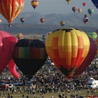 "Albuquerque, USA - October 12, 2007: Mass ascension of hot air balloons and crowd of people in the early morning at Balloon Fiesta Park. The Albuquerque International Balloon Fiesta is a world-renowned attraction with over 600 balloons and crowds for some events in excess of 100,000 people."