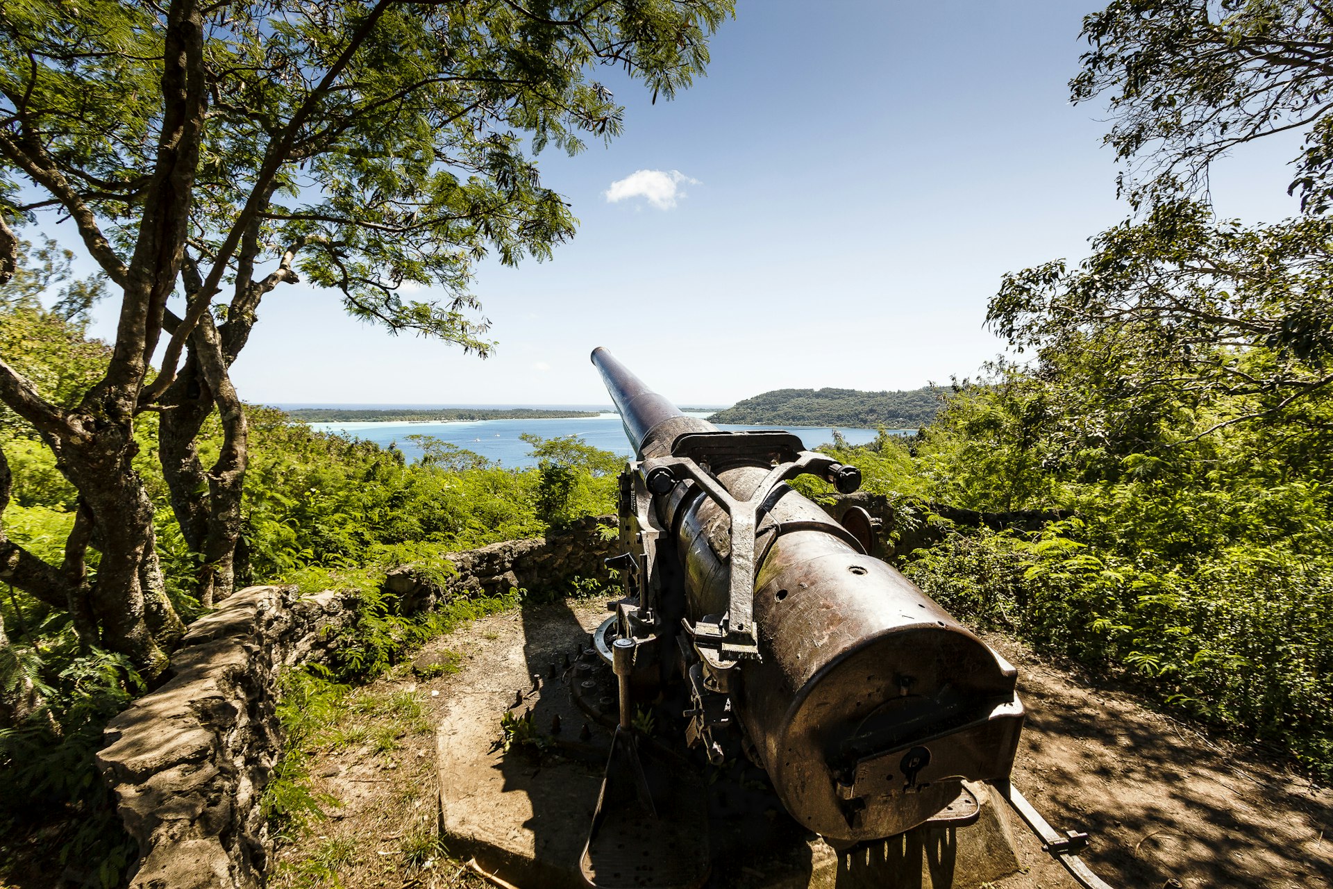 A World War II Cannon on a hilltop on the island of Bora Bora with beautiful views of the lagoon beyond