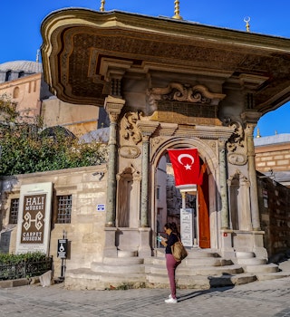 Istanbul, Turkey - October 29, 2019: An adult woman tourist with a guidebook in her hands at the entrance to the Carpet Museum in Istanbul. Turkish landmark in the old town