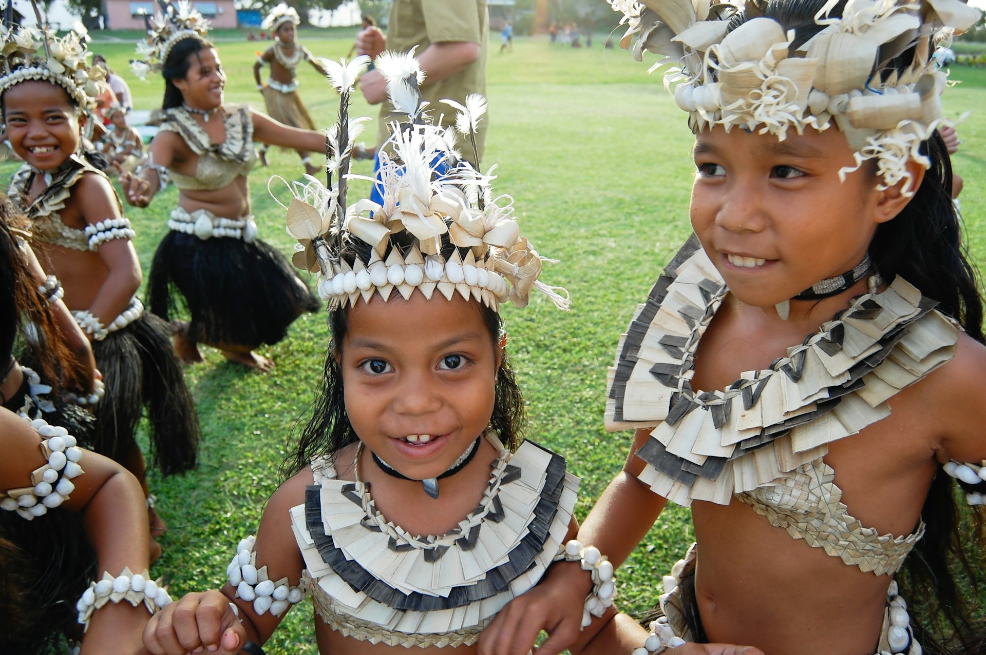 Children dressed in traditional Fijian outfits smile at the camera