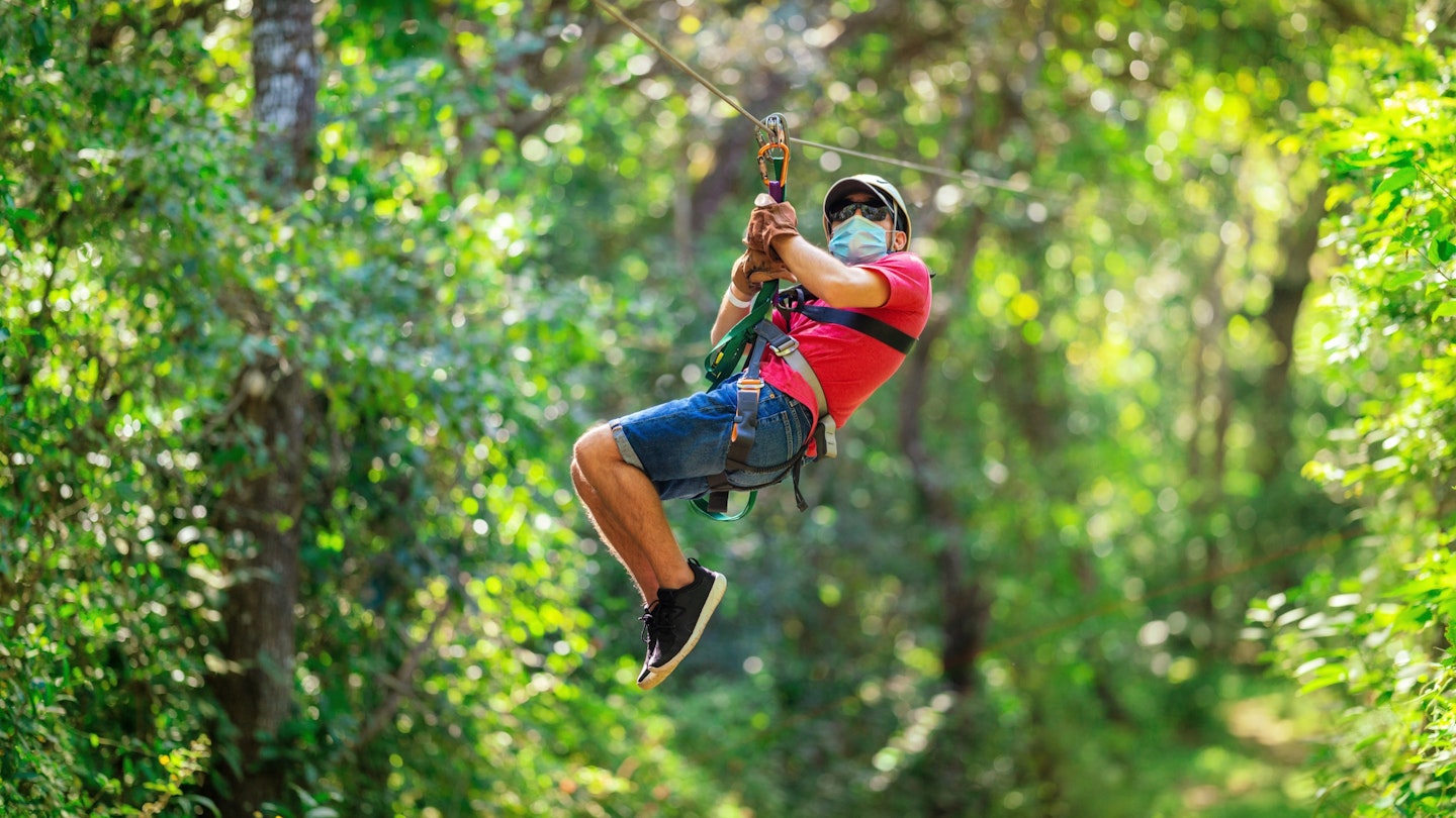 Boy teenager on a zip line in Costa Rica wearing protective mask