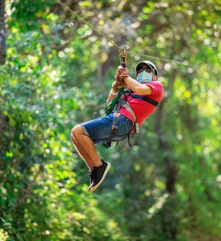 Boy teenager on a zip line in Costa Rica wearing protective mask