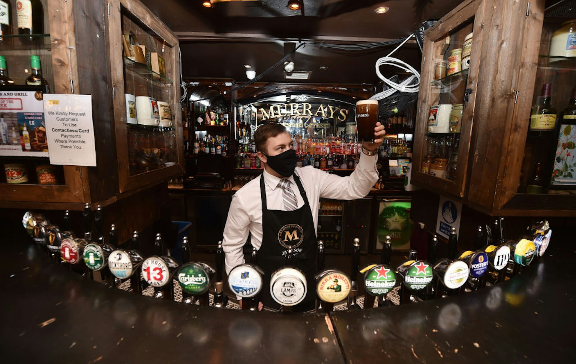 A barman in Murrays pub on Grafton street checks the head on a pint of Guinness on June 29, 2020 in Dublin, Ireland. Restaurants, pubs, cafes and hairdressers were among the businesses that can open across Ireland today provided they can observe social distancing rules to reduce transmission of the coronavirus.