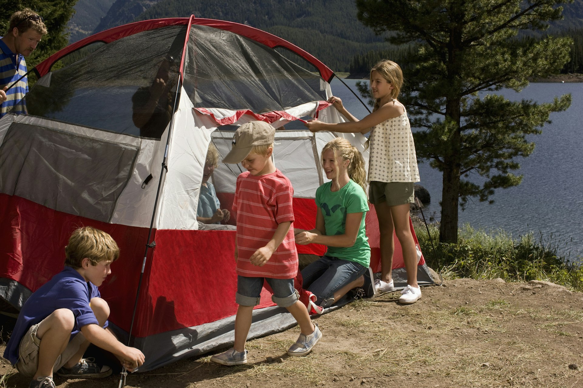 Family setting up tent by lake