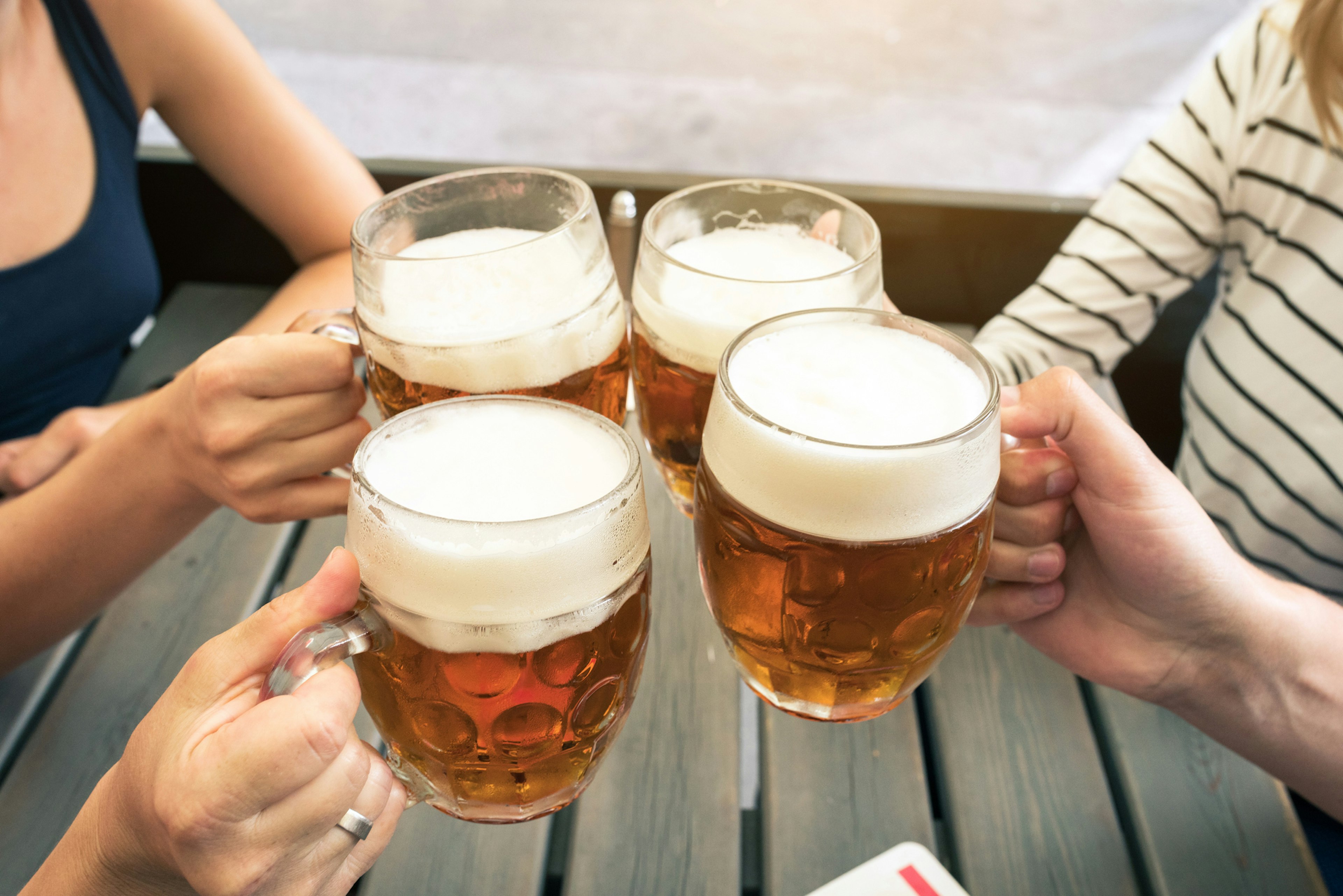 Four large glasses of beers being clinked together to say