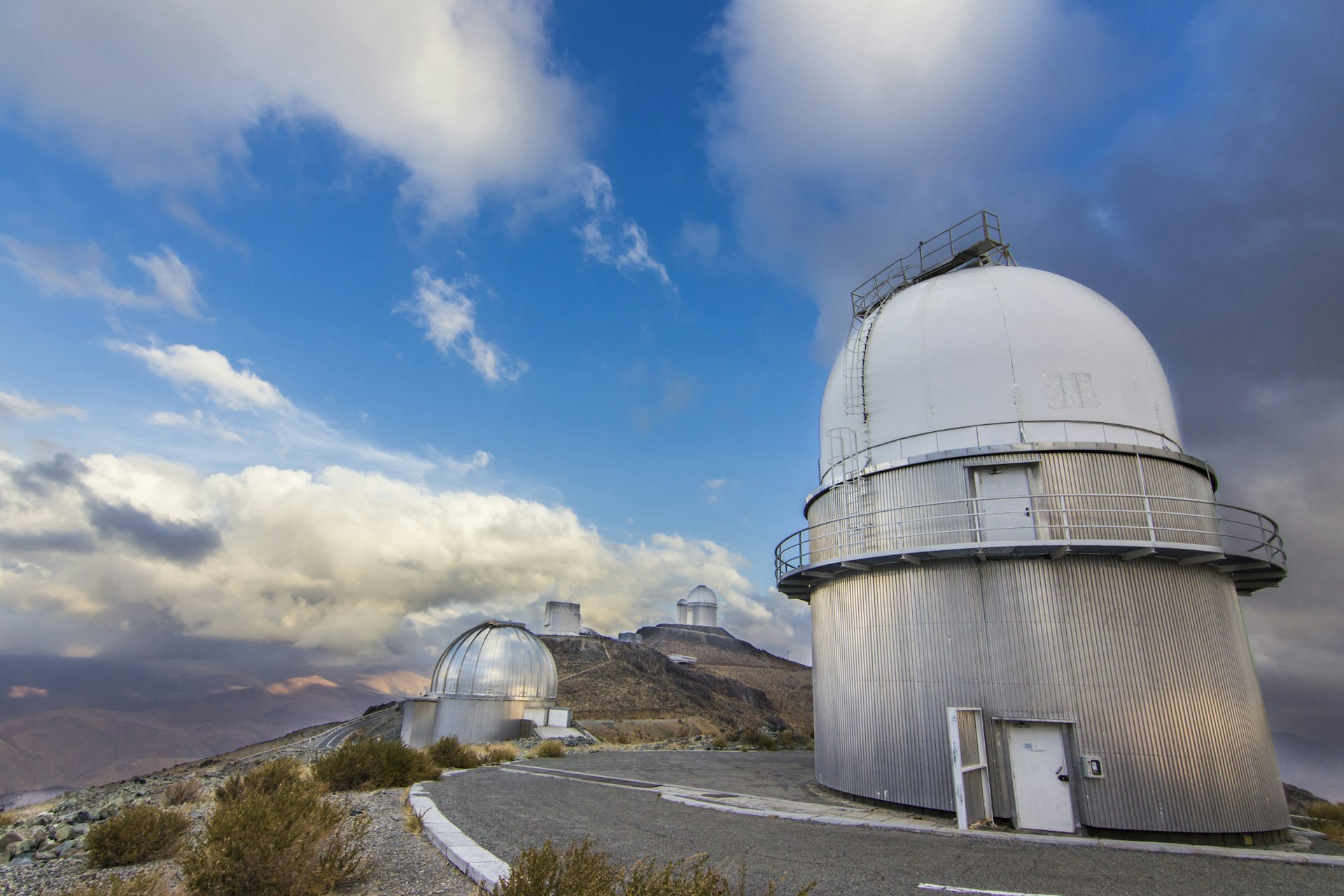 Several domed observatories lining a high ridge in a desert landscape