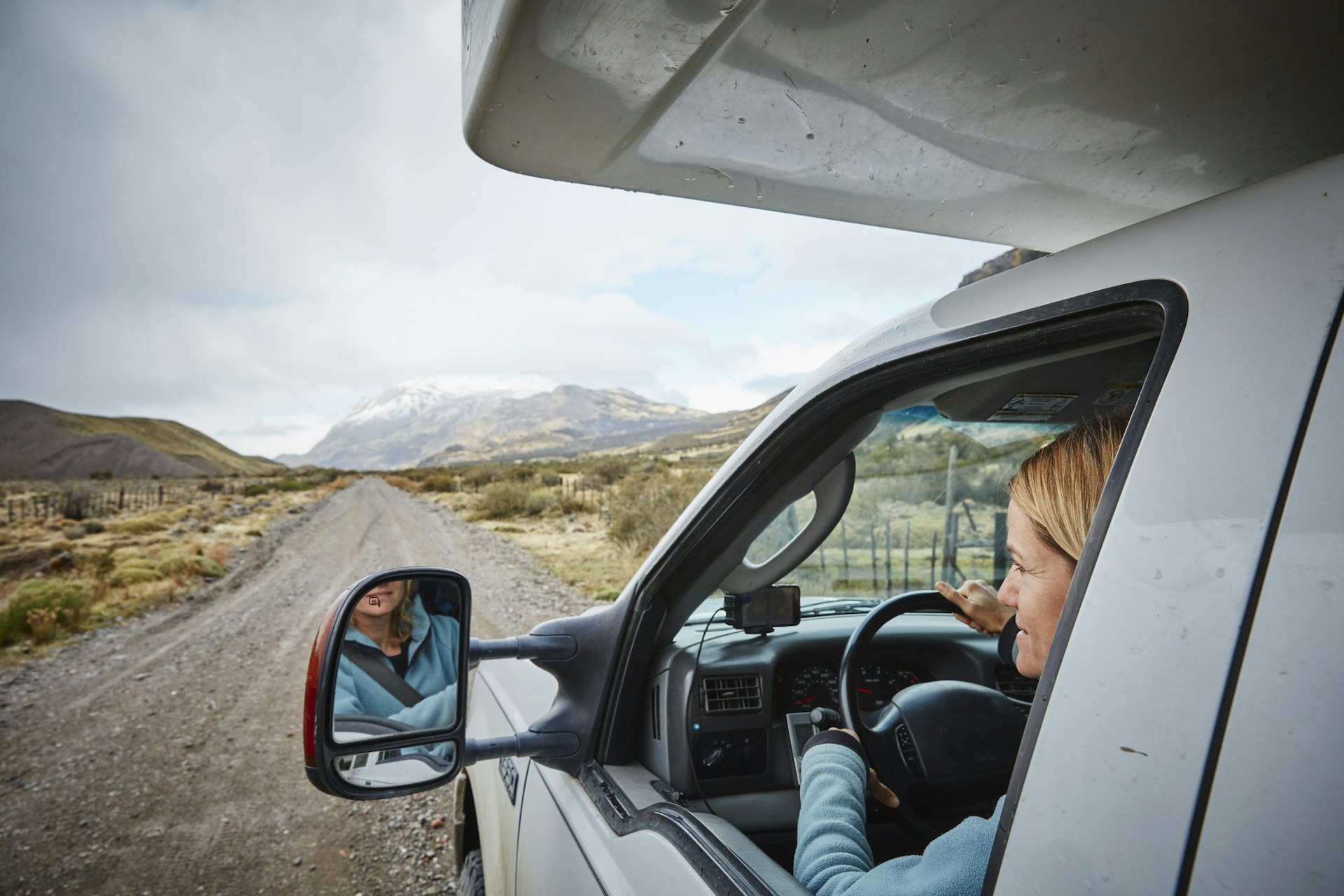 A woman looking out of the window of a campervan to admire the mountainous scenery