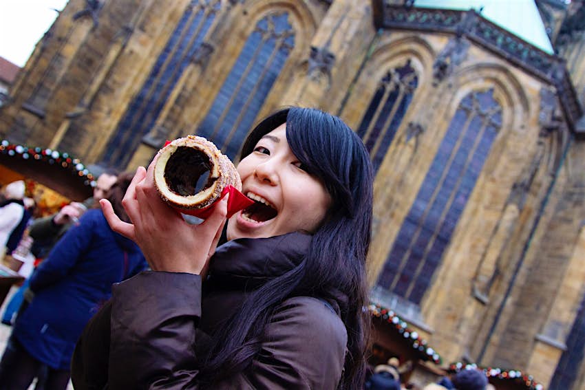 portrait of smiling young woman eating food in prague