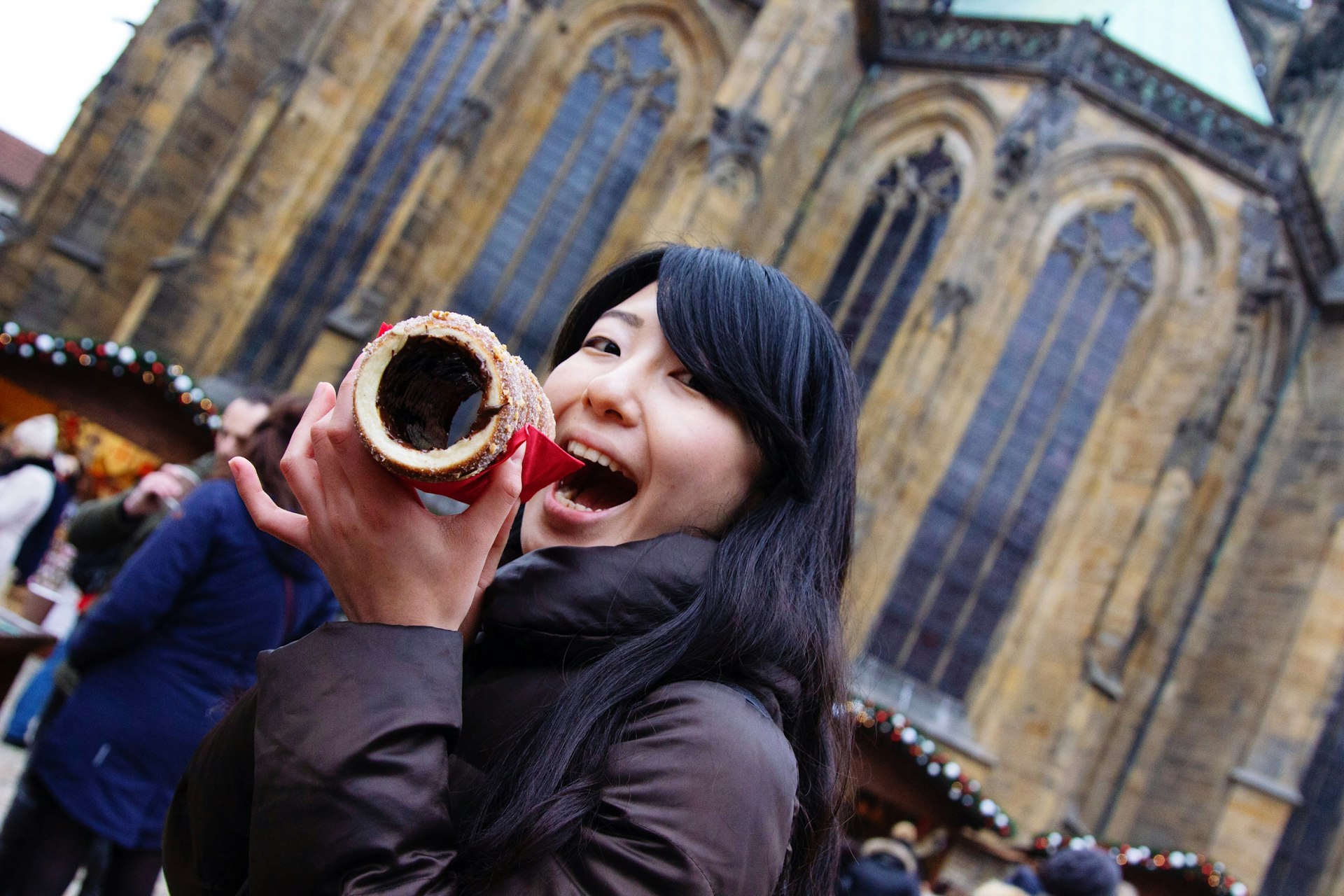 A woman smiles as she tucks into a pastry