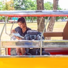 Young asian female traveler with backpack traveling sitting on taxi or Tuk Tuk and see map travel with old temple (Wat Mahathat) background, Ayutthaya Province, Thailand