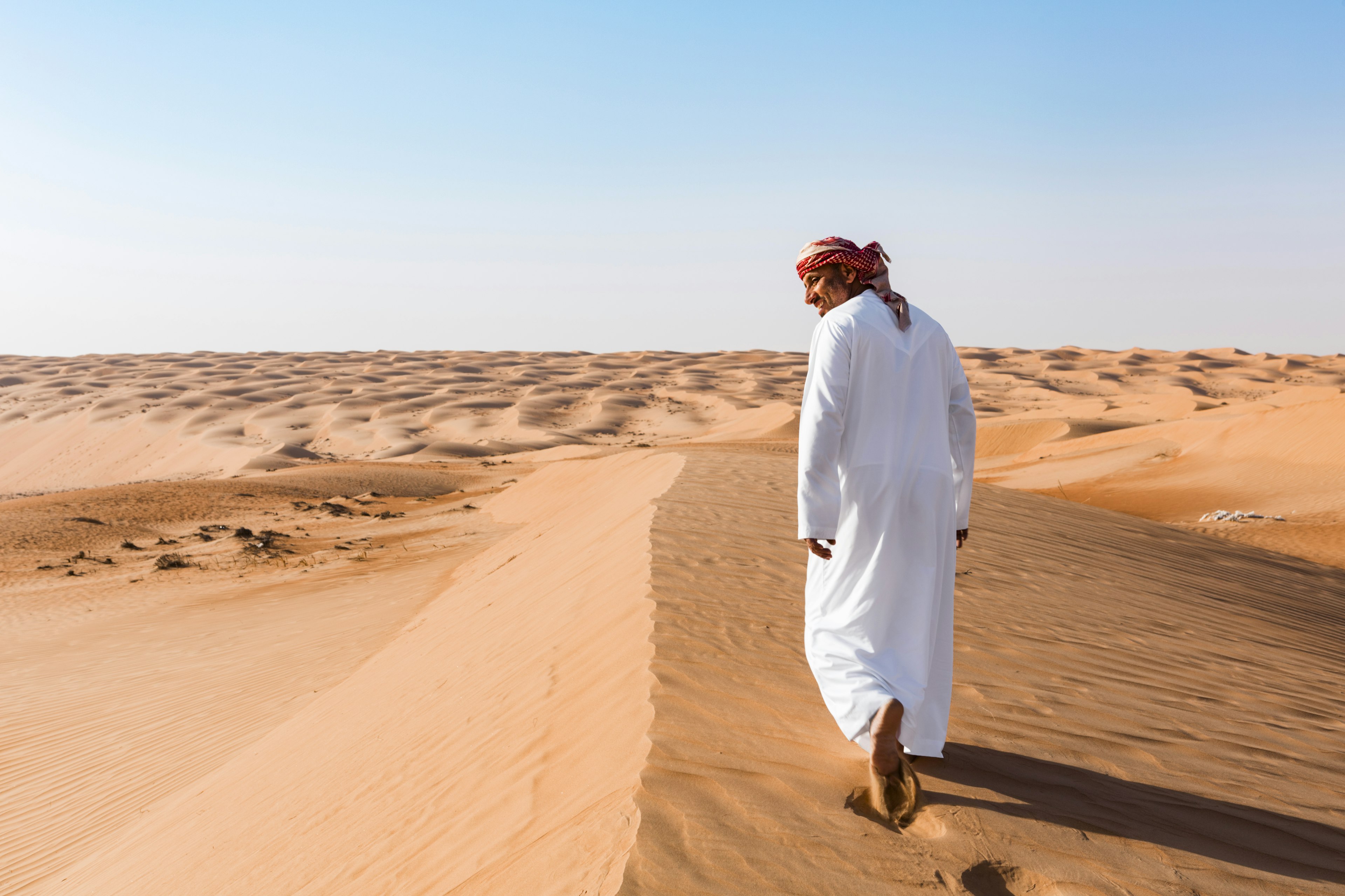 Bedouin walking in the desert, Wahiba Sands, Oman