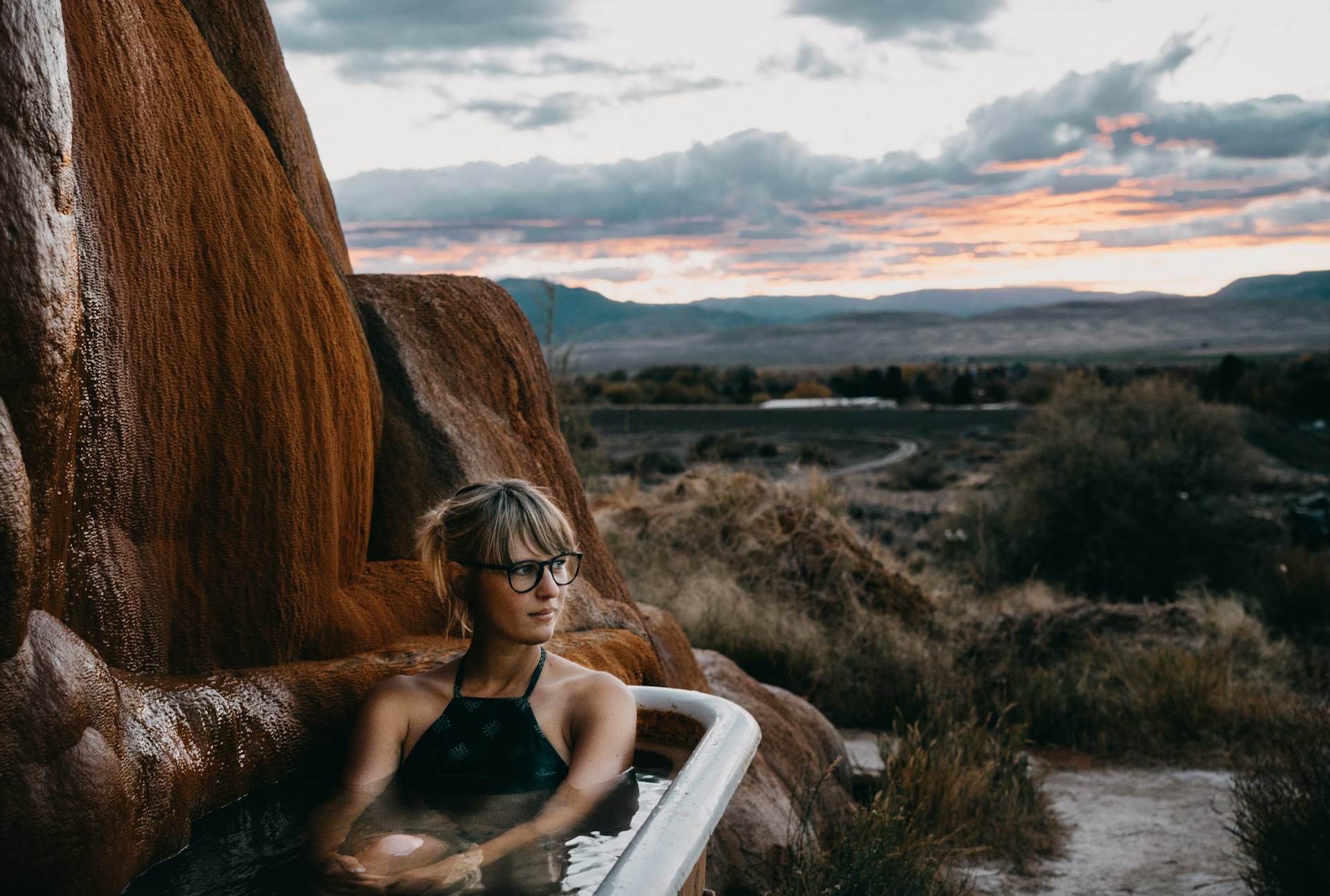 Woman sitting in a hot springs bathtub at Mystic Hot Springs in Utah during sunset