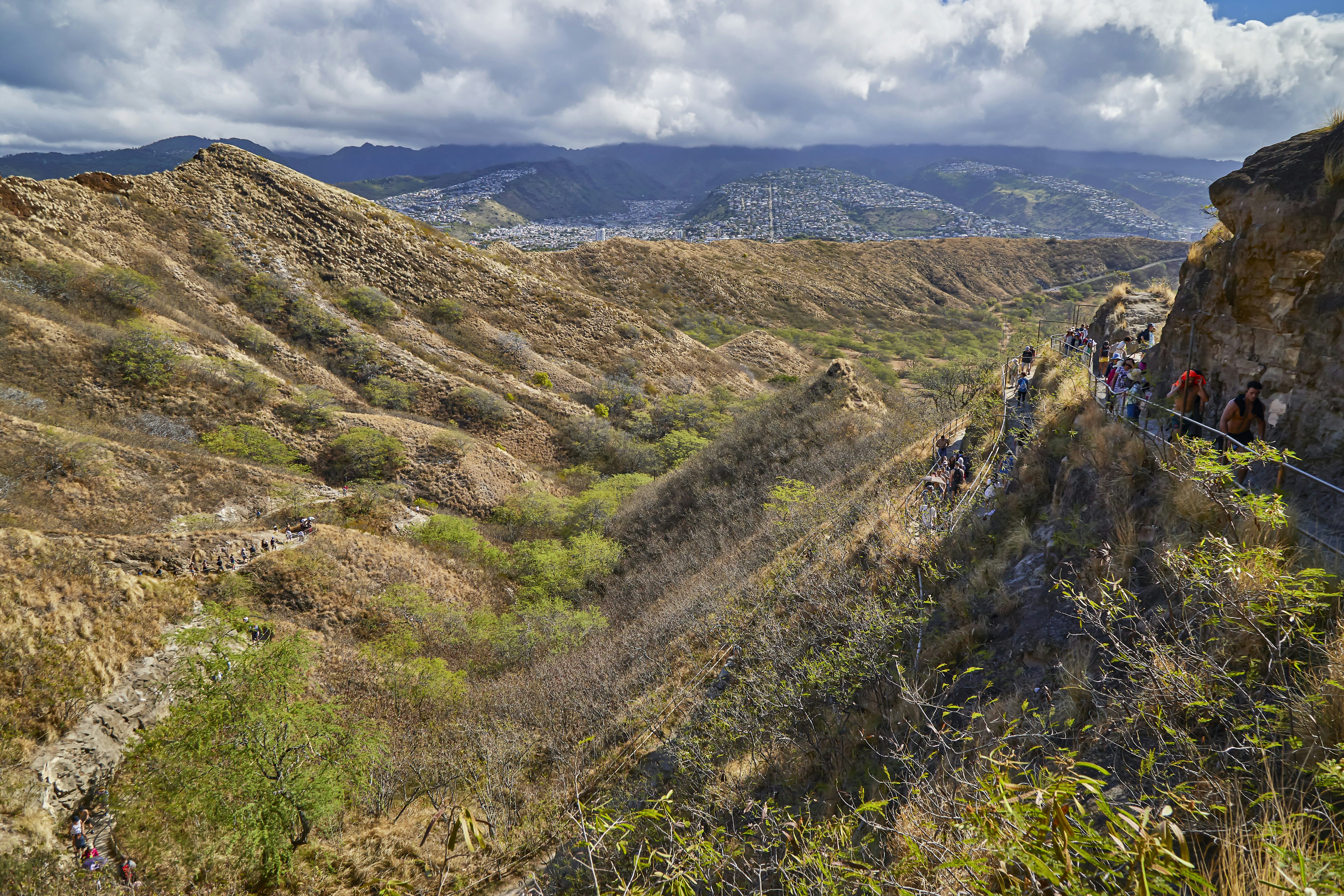 People walking along the walking path up and down to the top lookout of Diamond Head State Monument.