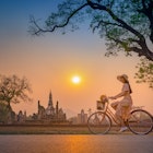 A woman cycling through the ruins of Ayuthaya