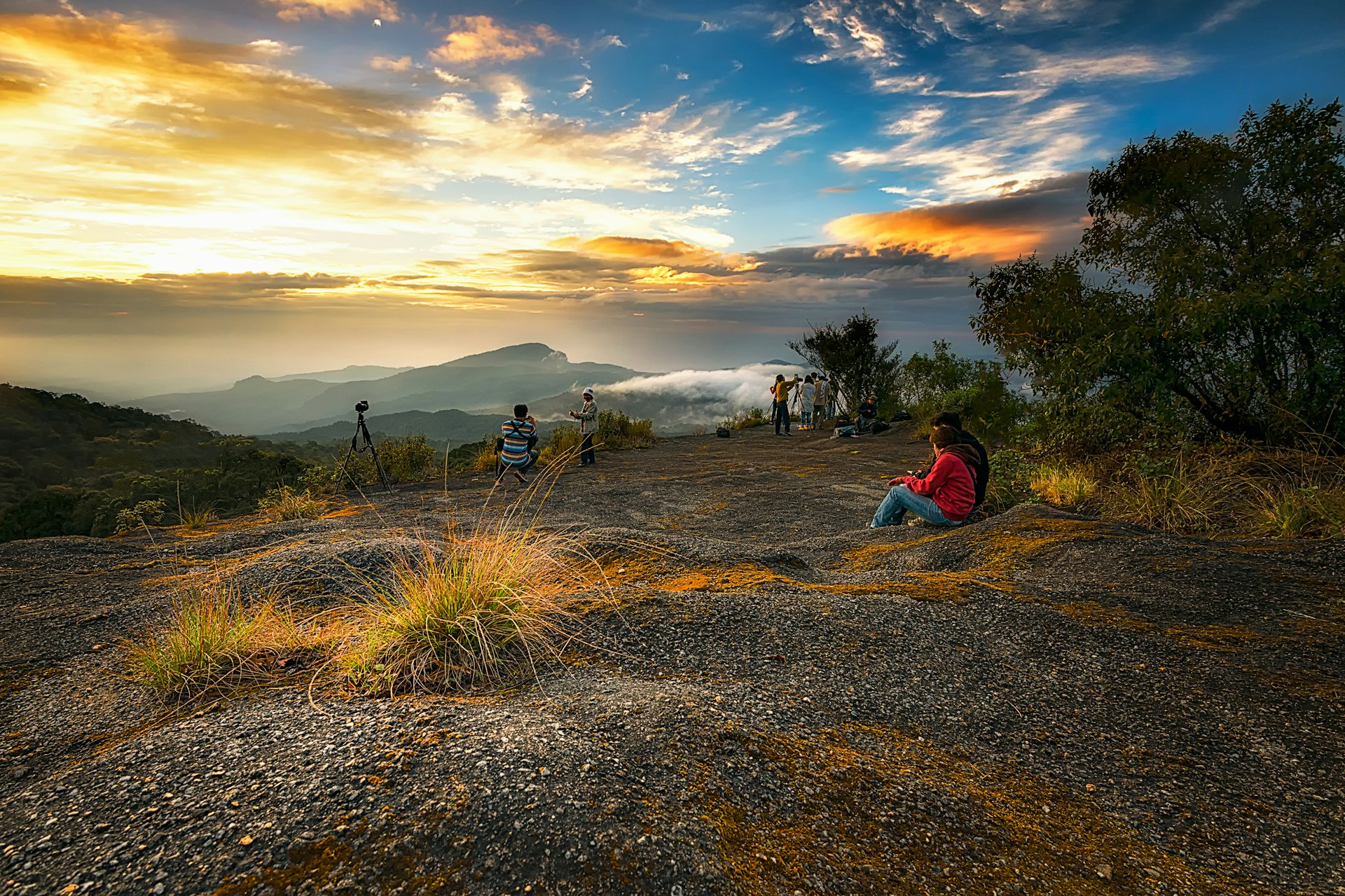 Groups of people watch the sunrise from a mountain viewpoint