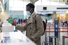 Young Man Wearing Mask Standing At Airport