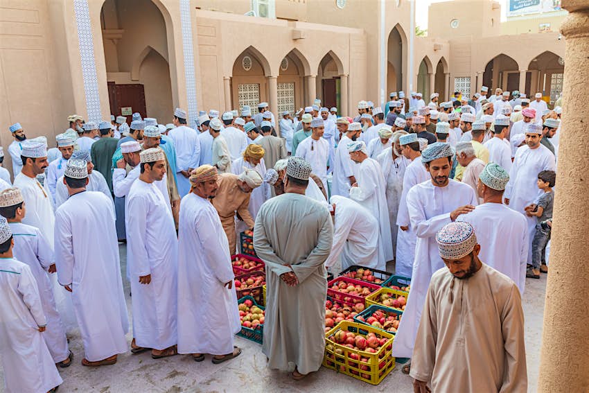 Men haggling over pomegranates at the souk in Nizwa, Oman