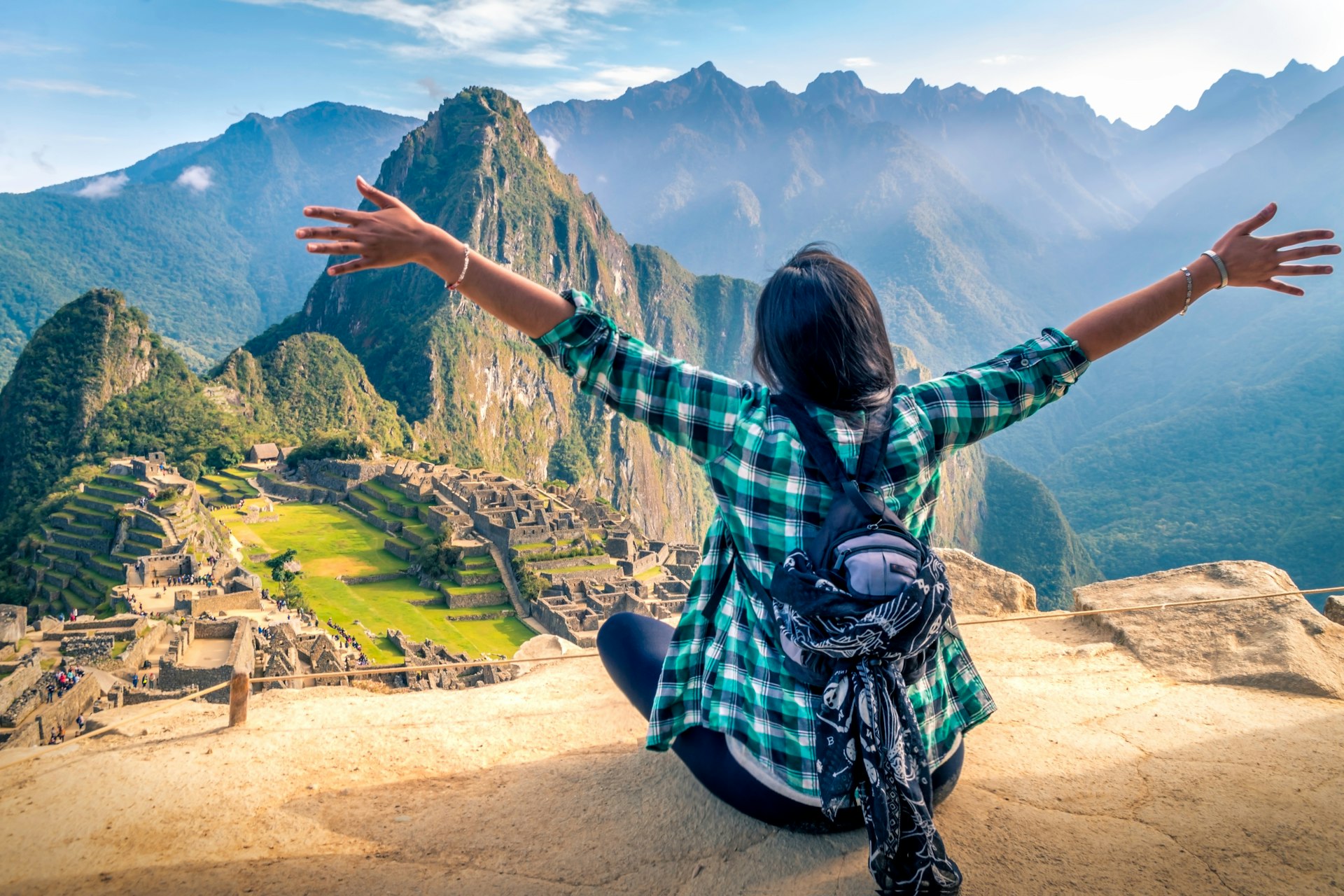 A woman tourist contemplating the amazing landscape of Machu Picchu with arms open