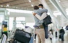 African man hugging and lifting woman at airport terminal. Couple meet after long separation at airport post pandemic lockdown.
