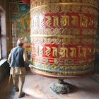 Old man turning a prayer wheel at Bodhnath Stupa, Nepal