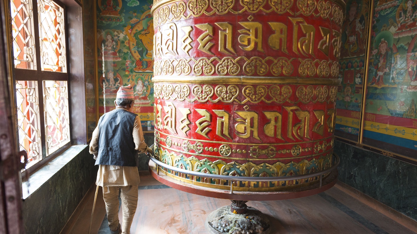 Old man turning a prayer wheel at Bodhnath Stupa, Nepal