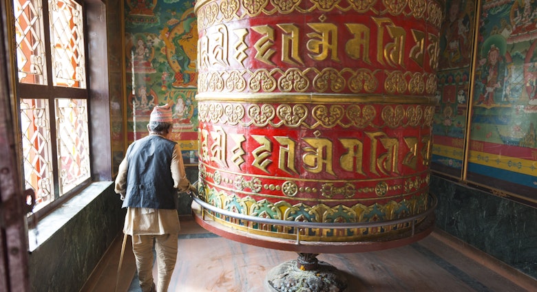 Old man turning a prayer wheel at Bodhnath Stupa, Nepal