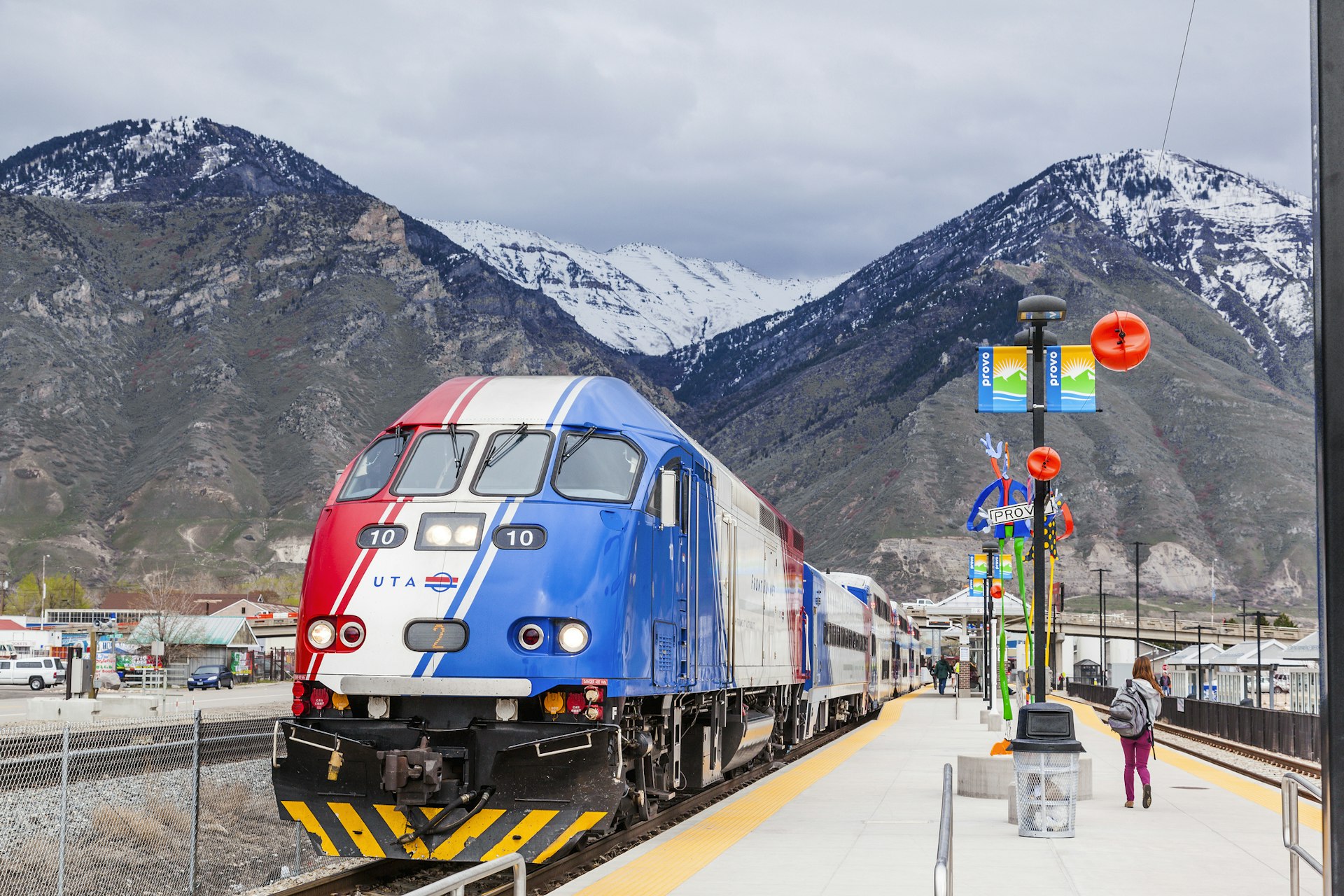 A red, white and blue train engine at a station in a mountainous area