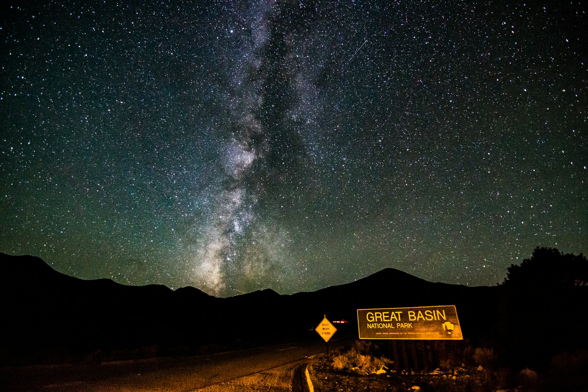 Information Sign On Road By Silhouette Mountains Against Star Field