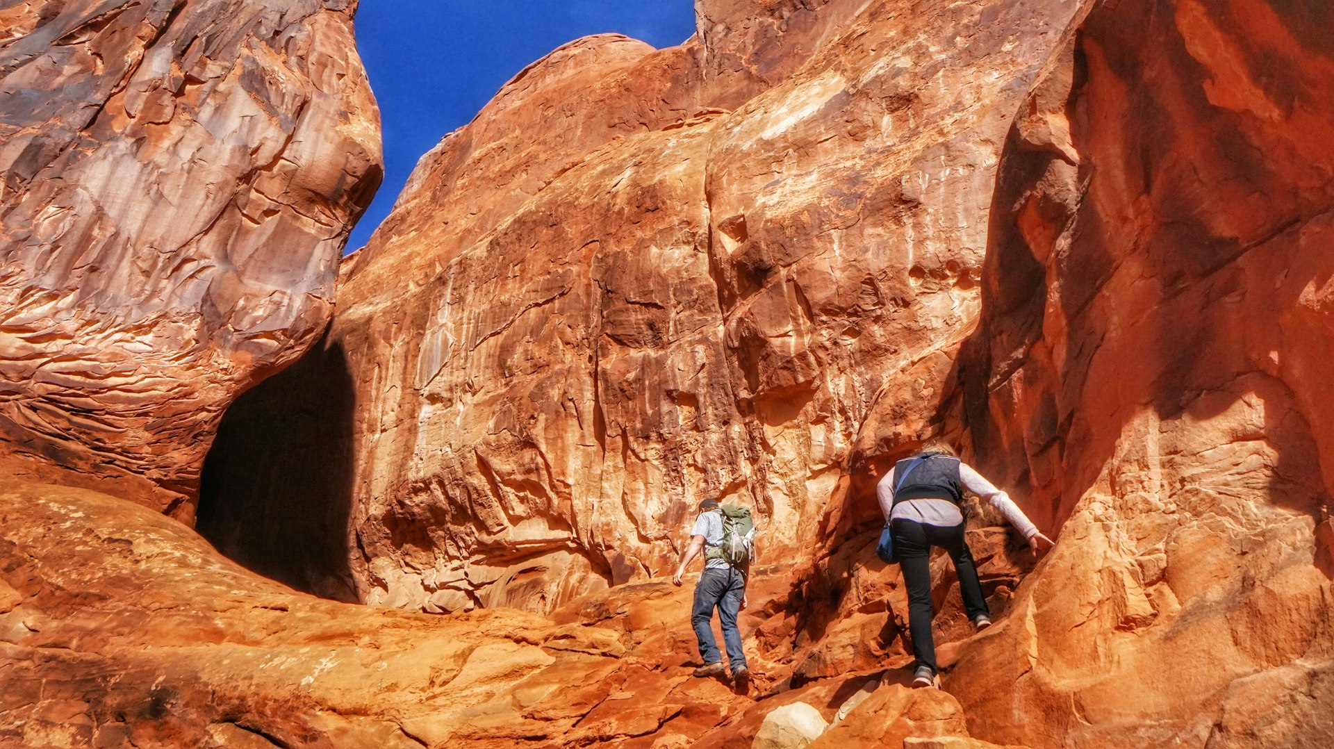 Two hikers climb rocks on the Fiery Furnace backcountry trail in Arches National Park, Utah