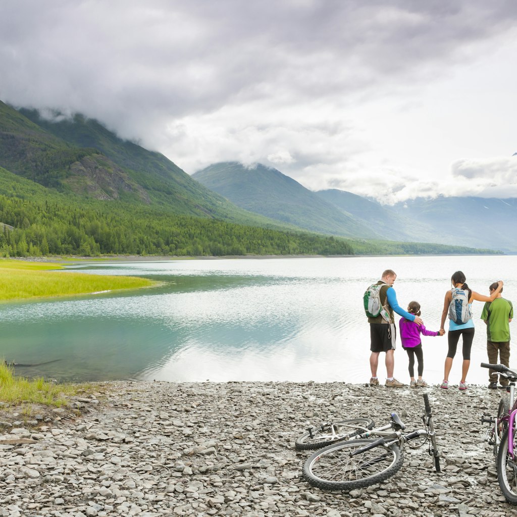 A family pauses on a cycle trip by an Alaskan beach