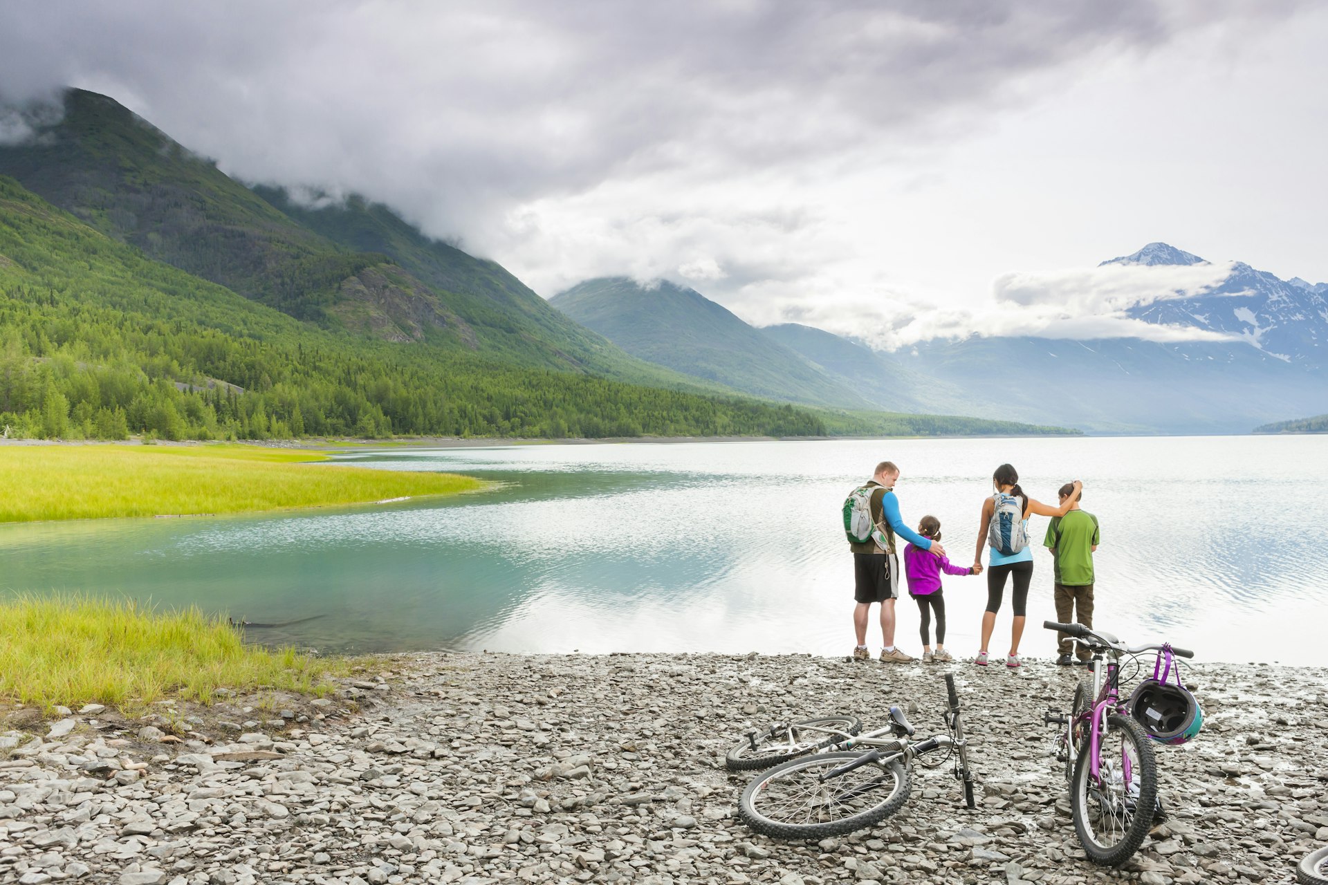 Couple with son and daughter riding bicycles near lake in Alaska