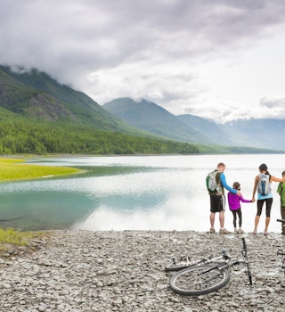 A family pauses on a cycle trip by an Alaskan beach
